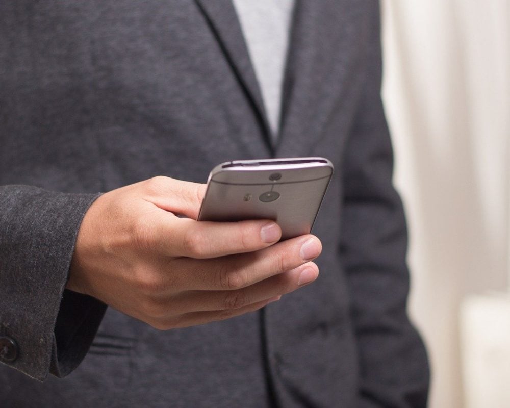 Mobile phone held in hand with screen showing incoming call icons, representing telephone call and communication.